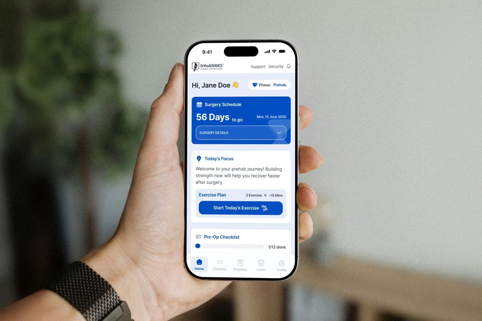 A hand holding a phone showing the OrthoADVANCE 360 patient app